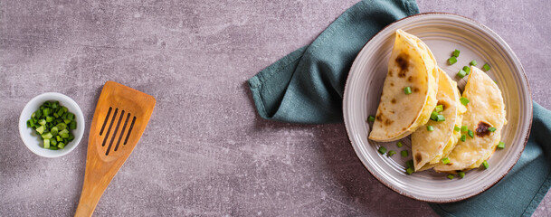 Thin tortillas filled with mashed potatoes and onions on a plate. Top view. Web banner.