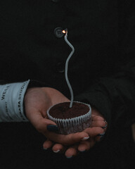 Hand holding a birthday cake with a candle