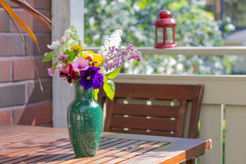 vase with summer flowers on the table on the terrace on a summer sunny day