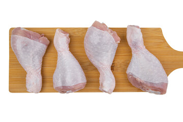 Raw chicken legs on a cutting board, isolated on white, top view, raw chicken meat, flat lay, copy space.
