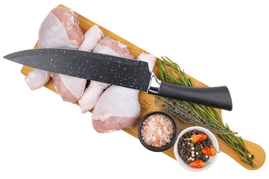 Raw chicken drumsticks on a cutting board with a knife and spices, top view, isolated on white, raw chicken meat, flat lay, copy space.
