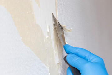 Person stripping wallpaper using a scraper hand tool. Do it yourself concept
