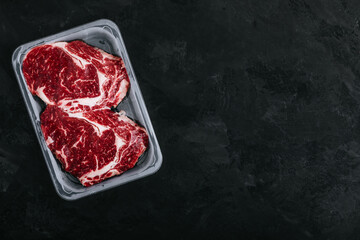 Ground Beef steak in vacuum packaging on dark stone background