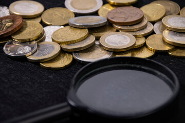 Coin collection and magnifying glass on black cloth