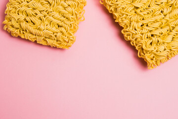 Flatlay, paper background with copy space. Two large servings of instant noodles on a pink background.