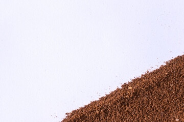 A pile of scattered ground coffee on a white background. The grains of ground black coffee are very close. Close up ground coffee background.