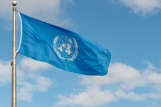 Fundy National Park, NB, Canada - June 30, 2020: United Nations flag flying in the wind on a flagpole against a partially cloudy sky.