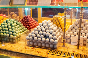 hand crafted chocolate bites a lot on shop window, store shelf. Heap of assorted chocolates. Candy balls of different types of chocolate.
