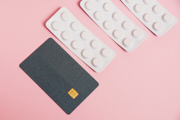 Flatlay, pills, money and bank card on a pink background. Concept of ordering medicine online