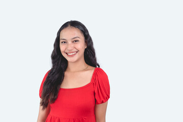 A simple young woman showing her beautiful smile. Smiling about a healthy love life, self-esteem and life. Wearing a red dress. Isolated in a white background.