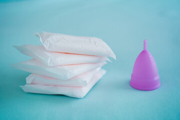 Menstrual cup and pads on a blue background, concept of critical days