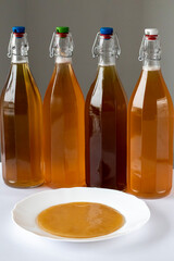 Kombucha is a drink made from sweet tea using a culture of bacteria and yeast. Four bottles with different additives in the background of a tea mushroom.