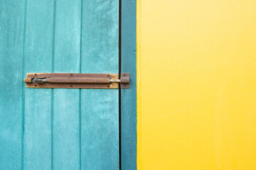 The Closed padlock hangs on the yellow and blue wall doors.