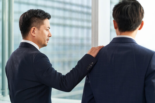 asian business man standing by the window in office consoling a colleague
