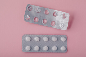 Pills in blister pack on pink background, top view