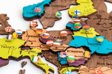 map of europe with flags, lots of round metal buttons with different flags of countries on the map of europe, wooden three-dimensional map of the world on a white background, politics, international