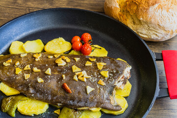 Baked sole with baker potatoes in black casserole