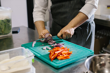 Obraz na płótnie Canvas Close up, male chef cuts vegetables in restaurant.