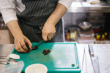 Fototapeta na wymiar The process of making muesli in a restaurant, the male chef cuts dates in the kitchen.