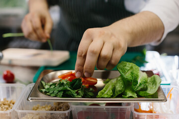 Preparing vegetables for a delicious bowl dish: a male chef in a contemporary restaurant kitchen.
