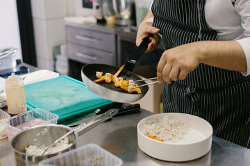 Obraz na płótnie Canvas Preparing a bowl of seafood, a male chef prepares a delicious dish in a restaurant kitchen.