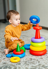 Curious smilling baby with colorful educational toy. Funny playful kid with toys.