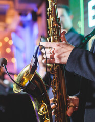 Obraz premium Concert view of saxophonist, a golden saxophone, sax player with vocalist and musical band during jazz orchestra show performing music on a stage in the scene lights