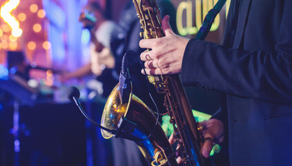 Concert view of saxophonist, a golden saxophone, sax player with vocalist and musical band during...
