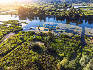 Aerial view of high-voltage power  tower passing through a wetland.