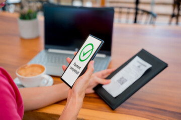 Woman using contactless payment by mobile phone with QR code at cafe