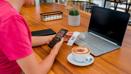 Woman using contactless payment by mobile phone with QR code at cafe