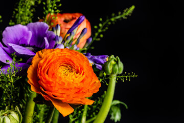Colorful bouquet with purple, orange and red flowers in front of black background