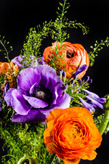 Colorful bouquet with purple, orange and red flowers in front of black background