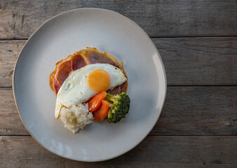 Egg breakfast with rice, ham and vegetable on a wooden table
