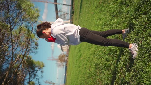 Dedicated female boxer dreesd hoodie warming up arm muscule. Athletic female prepares for boxing workout outdor in park. Female fitness motivation. Fighter warm up body before training. Vertical shoot