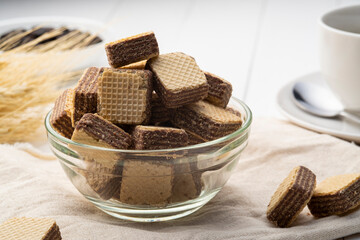 Wafer filled with cocoa cream flavored in glass bowl with cup coffee background