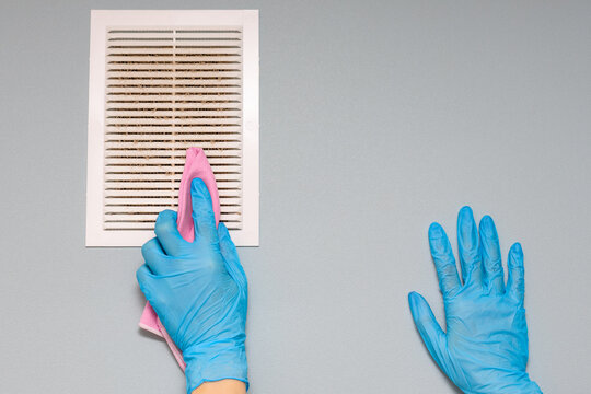 Man Cleaning The Ventilation Grill In The Room.