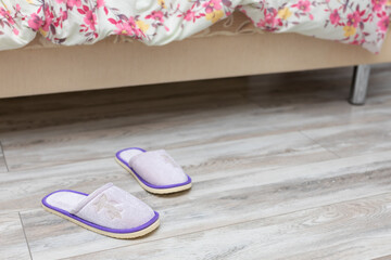 slippers near the bed on which the person sleeps.