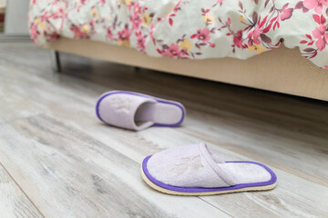 slippers near the bed on which the person sleeps.