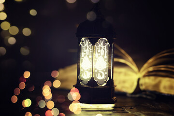 Ramadan Kareem background. Ornamental Arabic lantern glowing and the holy book of Quran.