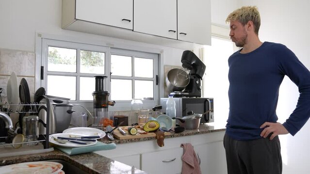 Caucasian man worried about the mess in his kitchen.