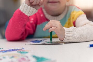 Prety 4 years old european or american  kid girl playing next to jigsaw puzzles while being at home in the winter. Joyfully On the table there are toys