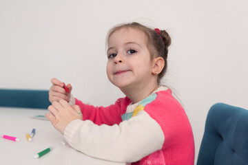 Prety 4 years old european or american  kid girl playing next to jigsaw puzzles while being at home in the winter. Joyfully On the table there are toys