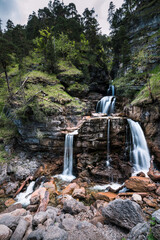 Wasserfall der sich teilt über Felsen im Wald mit grünen Bäumen und Moos. Kuhflucht Wasserfälle...
