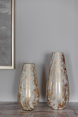 Decor item in the interior. Beautiful gilded glass vases on a marble stone in the house.