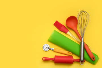 culinary accessories, dough knife, rolling pin, silicone mat, brush, whisk, ladle on a yellow background with copy space