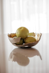 Abstract gold vase with fruit on the table in the living room interior. Modern gold interior of home. Green grapefruits. 