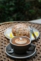 Latte art coffee with almond croissant on a wooden table