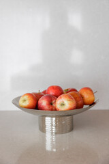 Abstract gold vase with fruit on the table in the living room interior. Modern gold interior of home. Red apples. 