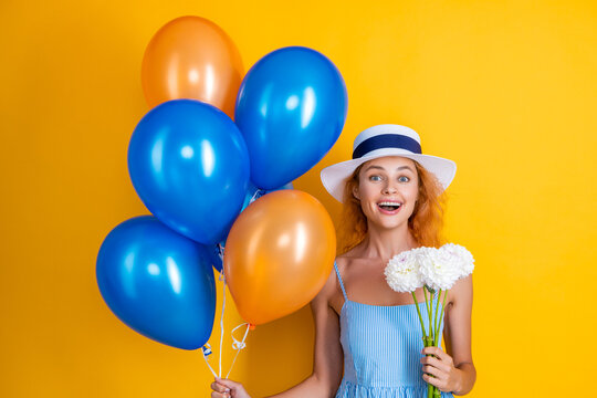 surprised birthday girl with balloons and flowers isolated on yellow. birthday girl with balloons